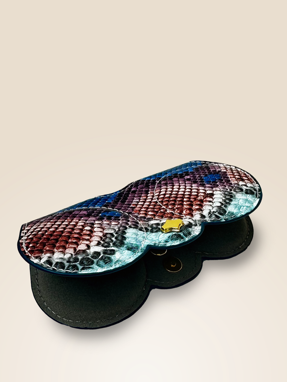 Front view of an eyewear case charm with a python-inspired pattern in blue, pink, and black, crafted from vegan leather. The case is partially open, showcasing its magnetic snap closure with gold-tone hardware, designed for easy access while keeping eyewear secure.